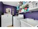 Well-organized laundry room featuring a washer, dryer, utility sink, storage shelves, and purple walls at 553 Circlewood Dr # T11, Venice, FL 34293