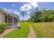 A lush backyard with green grass and trees, viewed from the side of the house at 5641 Hidden Oak Ct, North Port, FL 34287
