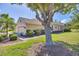 Tan home with a well-manicured lawn, mature trees, and a three-car garage at 5641 Hidden Oak Ct, North Port, FL 34287