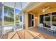 View of a screened lanai, featuring two chairs and a small table, overlooking the yard at 5641 Hidden Oak Ct, North Port, FL 34287