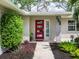 Charming front entrance with a vibrant red door and manicured greenery at 608 Apalachicola Rd, Venice, FL 34285