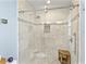 White tiled walk-in shower with glass door, mosaic tile accents, shower bench, and shower niche at 608 Apalachicola Rd, Venice, FL 34285