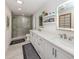 Bright bathroom featuring double sink vanity, large mirror, and a glass-enclosed shower, creating a modern and luxurious feel at 616 Gardenia Dr, Venice, FL 34285