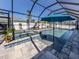 Lovely in-ground pool and spa beneath a screen enclosure, complemented by an umbrella and lounge chairs for relaxed outdoor living at 616 Gardenia Dr, Venice, FL 34285