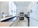 Open kitchen features white cabinets, stainless steel appliances, eat-in bar, and flows into adjacent living area at 633 White Pine Tree Rd # 27, Venice, FL 34285