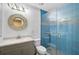 Modern bathroom features walk-in shower with blue tile, sleek vanity, and stylish round mirror at 6724 Schooner Bay Cir # 6724, Sarasota, FL 34231