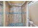 Shower features glass doors, tile surround, rain-style shower head, and pebble flooring at 6724 Schooner Bay Cir # 6724, Sarasota, FL 34231
