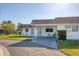 The house has a white exterior, brown roof, covered parking, green lawn, and clear blue sky at 680 Circlewood Dr # W3, Venice, FL 34293