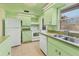 Well-lit kitchen with classic green cabinetry, stainless steel sink, and white appliances at 680 Circlewood Dr # W3, Venice, FL 34293
