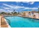 Community pool featuring clear blue water, lounge chairs, and a pool house against a partly cloudy sky at 680 Circlewood Dr # W3, Venice, FL 34293