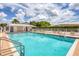 Community pool featuring clear blue water and lounge chairs, with a pool house against a cloudy sky at 680 Circlewood Dr # W3, Venice, FL 34293