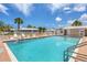 Community pool featuring clear blue water and lounge chairs, with palm trees and a cloudy sky at 680 Circlewood Dr # W3, Venice, FL 34293