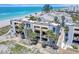 Exterior view of three-story beachfront condo with private balconies and swaying palm trees at 700 Golden Beach Blvd # 115, Venice, FL 34285