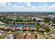 Aerial view of the home featuring a tile roof, a well-manicured lawn, and tranquil lake views at 744 Fringed Orchid Trl, Venice, FL 34293