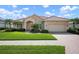 Charming single-story home featuring a red tile roof, paver driveway, and lush green landscaping at 744 Fringed Orchid Trl, Venice, FL 34293