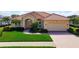 Charming single-story home featuring a red tile roof, paver driveway, and lush green landscaping at 744 Fringed Orchid Trl, Venice, FL 34293