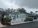 Quaint mobile home with light gray exterior, decorative shrubs, and plenty of windows for natural light at 795 Cervina N Dr, Venice, FL 34285