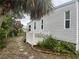 Exterior side view of home with small garden featuring various foliage and a white picket fence at 795 Cervina N Dr, Venice, FL 34285