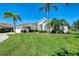 Inviting home with a lush green lawn, mature trees, and colorful flower beds create a warm curb appeal at 854 Blue Crane Dr, Venice, FL 34285