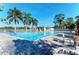 Beautiful community pool with clear blue water, lounge chairs, and tropical landscaping under a bright blue sky at 854 Blue Crane Dr, Venice, FL 34285
