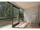 Screened-in lanai with a view of lush landscaping and a rocking chair at 930 Capri Isles Blvd # 120, Venice, FL 34292