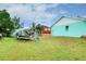 Backyard view featuring a trailer with boat, small shed with a tarp cover, and grass area at 990 Sea Fox Rd, Venice, FL 34293