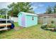 Backyard view showcasing a shed with a lavender door, garden with flowers, and trailer with boat at 990 Sea Fox Rd, Venice, FL 34293