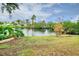 Beautiful backyard view showcasing lush landscaping and a tranquil pond on a partly cloudy day at 990 Sea Fox Rd, Venice, FL 34293