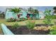 Charming home with vibrant landscaping, featuring palm trees, various plants, and a well-manicured lawn at 990 Sea Fox Rd, Venice, FL 34293