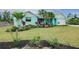 Charming home with a vibrant turquoise exterior, complemented by a lush, landscaped front yard and tropical plants at 990 Sea Fox Rd, Venice, FL 34293