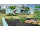 Landscaped front yard with mulched flower bed, vibrant plants, and a well-maintained lawn at 990 Sea Fox Rd, Venice, FL 34293
