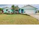 A vibrant and cheerful turquoise home with well-manicured lawn and colorful landscaping welcomes visitors at 990 Sea Fox Rd, Venice, FL 34293