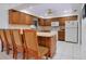 Traditional-style kitchen features wood cabinets, white appliances, and a breakfast bar with seating for four at 990 Sea Fox Rd, Venice, FL 34293