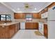 Well-lit kitchen features wood cabinets, white appliances, and tile flooring for easy maintenance at 990 Sea Fox Rd, Venice, FL 34293