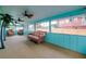 Bright sunroom features ample seating, ceiling fans, and large windows with cheerful, bright blue trim at 990 Sea Fox Rd, Venice, FL 34293