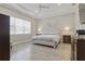 A bright bedroom featuring tray ceilings, a ceiling fan, and light gray wood flooring at 10136 Coral Shore Dr, Englewood, FL 34223