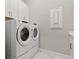 Bright laundry room with Whirlpool washer and dryer, white cabinetry and marble tile flooring at 10136 Coral Shore Dr, Englewood, FL 34223