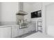 Outdoor kitchen including sink, stainless steel grill and hood, countertops and adjacent table at 10136 Coral Shore Dr, Englewood, FL 34223