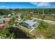 Aerial view of modern home near canal, showcasing outdoor pool, fenced yard, and surrounding landscape at 106 Playmore Dr, Venice, FL 34293