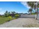 Modern home with a gravel driveway, privacy fence, and lush tropical landscaping at 106 Playmore Dr, Venice, FL 34293