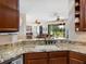 Kitchen with granite countertops and breakfast bar overlooking the living area and lush outdoor views at 11343 Bertolini Dr, Venice, FL 34292