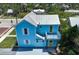 Aerial view of light blue two-story home shows balcony, metal roof, yellow doors and lush greenery surrounding the property at 121 Dolly St, Punta Gorda, FL 33950