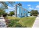 Charming blue two-story home boasts a stone chimney and a vibrant yellow door, creating a welcoming curb appeal at 121 Dolly St, Punta Gorda, FL 33950