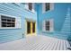 Charming light blue home exterior features a yellow door, white trim, and a spacious wooden patio at 121 Dolly St, Punta Gorda, FL 33950