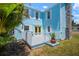 Light blue home featuring a private deck area, complemented by lush greenery and a charming stone chimney at 121 Dolly St, Punta Gorda, FL 33950