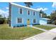 A charming, light blue home with white trim features a striking stone chimney and a cheerful yellow door at 121 Dolly St, Punta Gorda, FL 33950