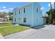 Light blue two-story home shows an additional balcony and yellow door with well-manicured lawn, offering a warm welcome at 121 Dolly St, Punta Gorda, FL 33950