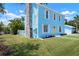 Light blue home features a stone chimney, a welcoming yellow door, and lush green lawn with flower beds at 121 Dolly St, Punta Gorda, FL 33950