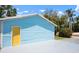 A light blue garage features a yellow door, a spacious concrete driveway and a neatly landscaped yard at 121 Dolly St, Punta Gorda, FL 33950