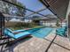 Relaxing screened-in pool with lounge chairs on a brick patio, surrounded by a manicured lawn at 1231 Pine Needle Rd, Venice, FL 34285